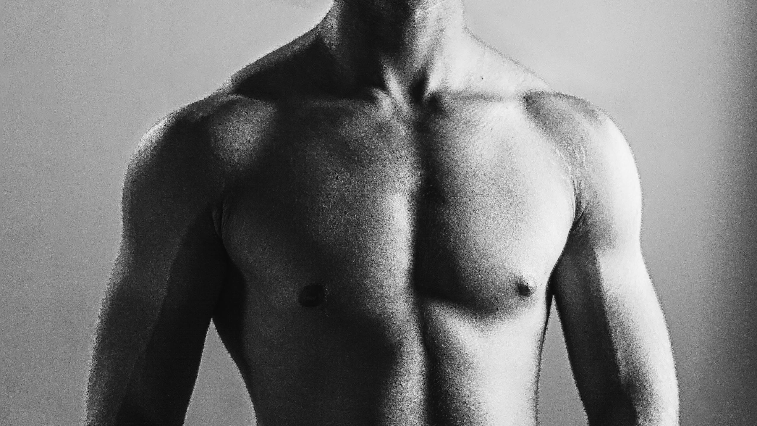 Grayscale photo highlighting muscular physique and masculinity of a shirtless man.