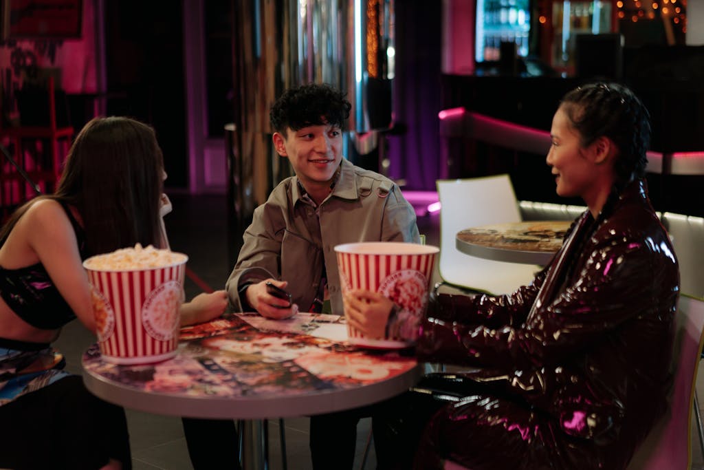 Group of diverse friends sharing popcorn and laughs in a trendy lounge setting.