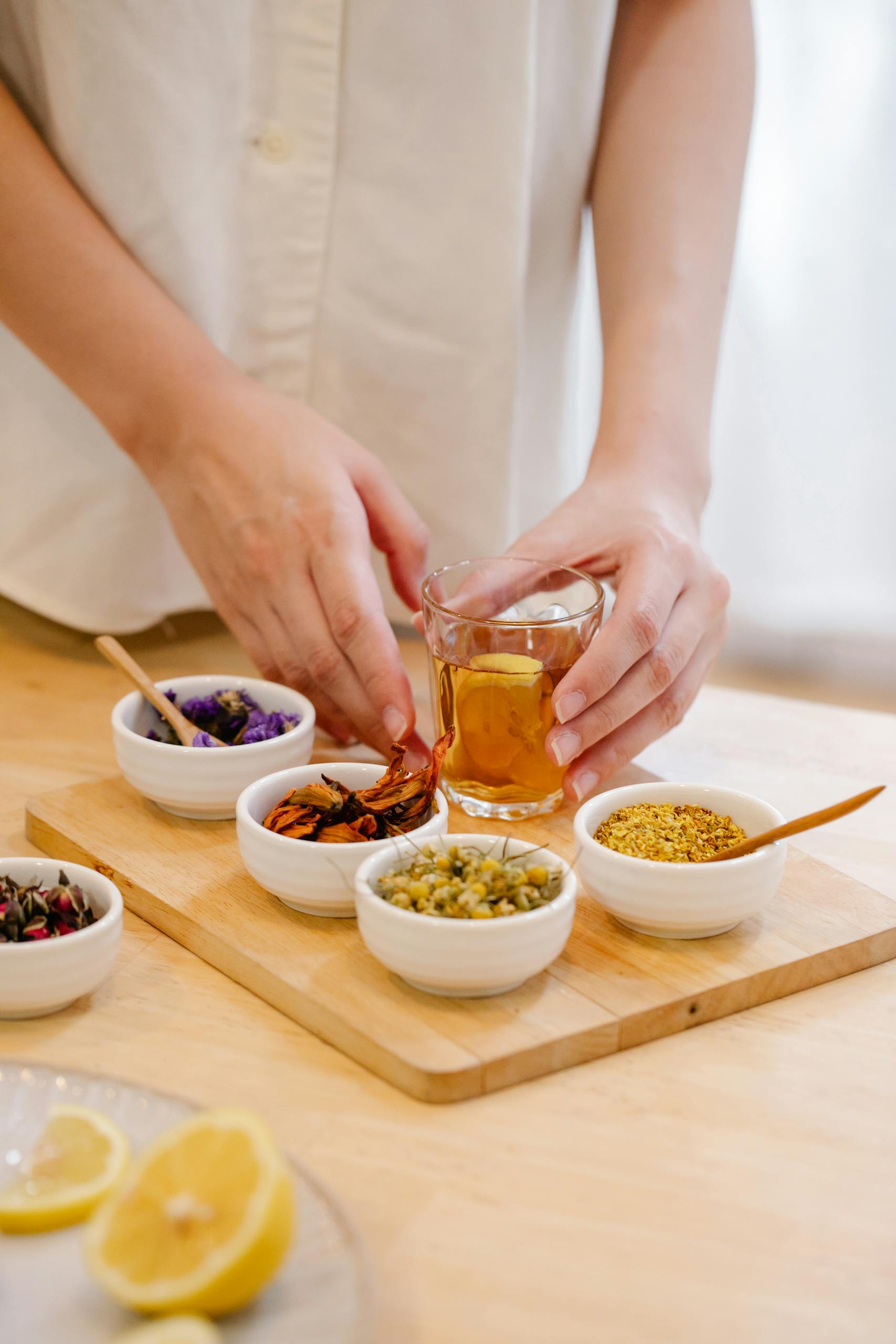 Hands arranging herbs for herbal tea with lemon slices, perfect wellness concept.