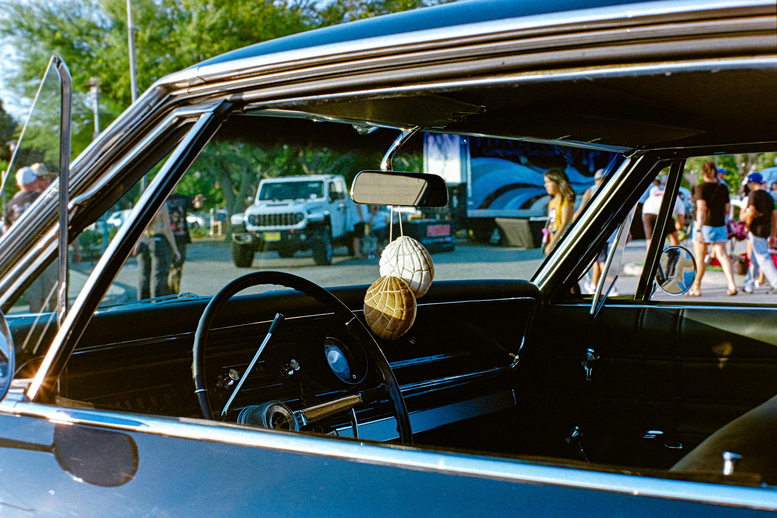 Interior of a classic car parked outdoors, showcasing vintage design elements and event atmosphere.