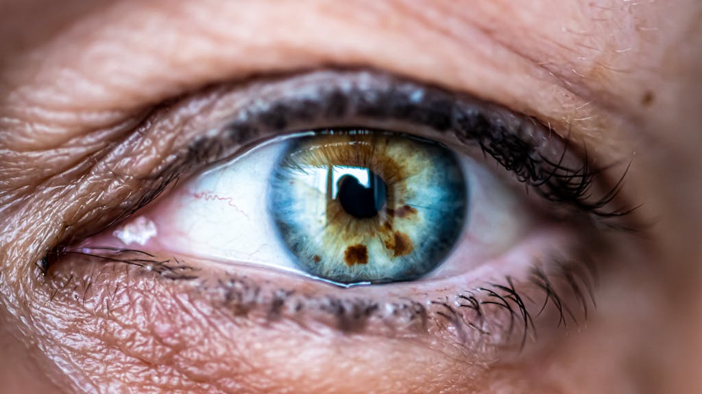 Macro shot capturing the intricate details of a blue and brown human eye, highlighting unique patterns.