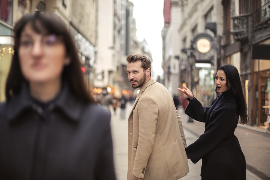 Man and woman in stylish attire on a vibrant city street, expressing surprise.