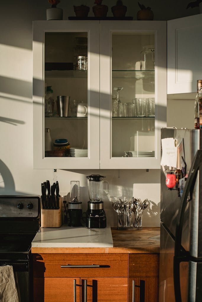 Modern comfortable kitchen with various utensil and appliances placed in cupboard and on wooden cabinet