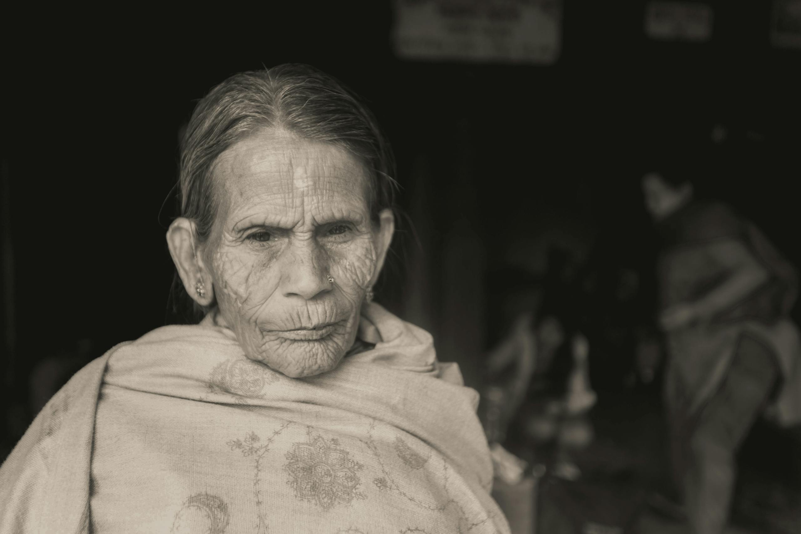 Moody grayscale portrait of an elderly woman in a shawl, highlighting age and wisdom.