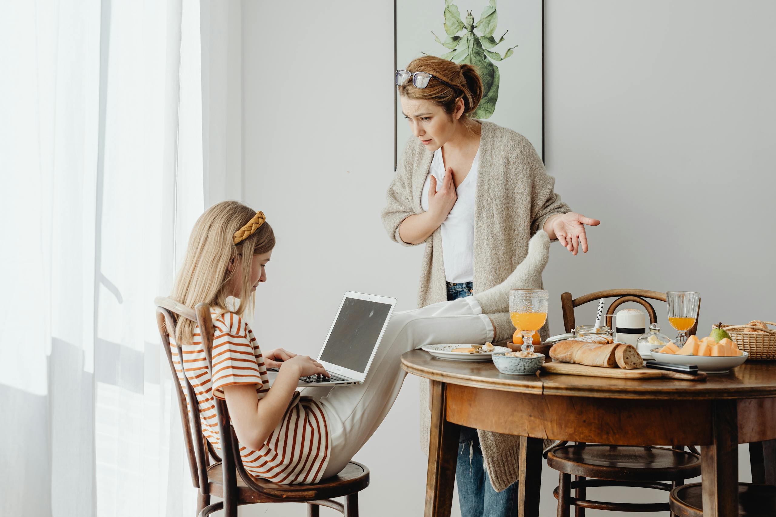 Mother and daughter having a discussion over breakfast with a laptop.