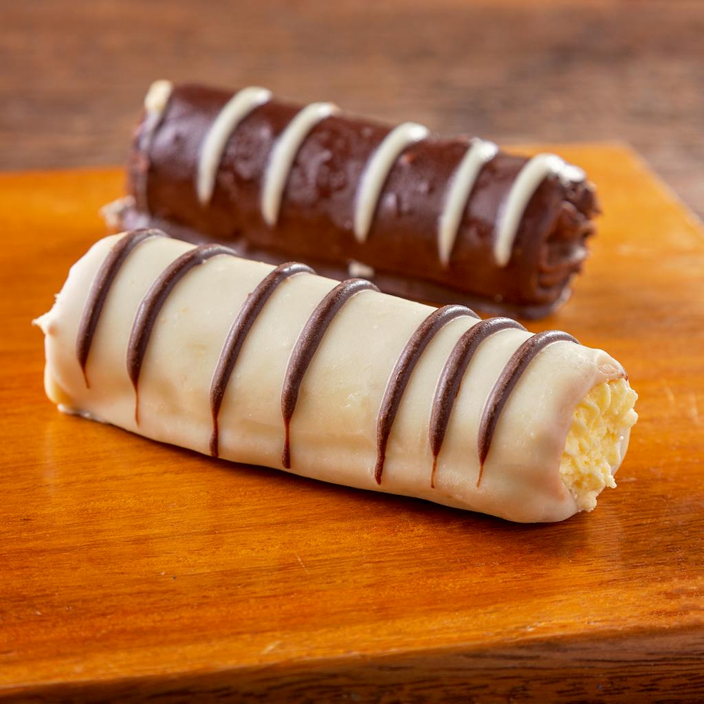 Mouthwatering chocolate and cream wafer rolls on a wooden board, perfect for dessert lovers.