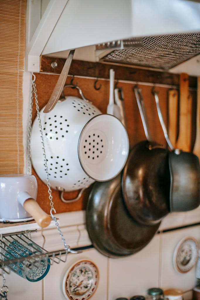 Part of kitchen interior with different utensils hanging on wall under exhaust hood