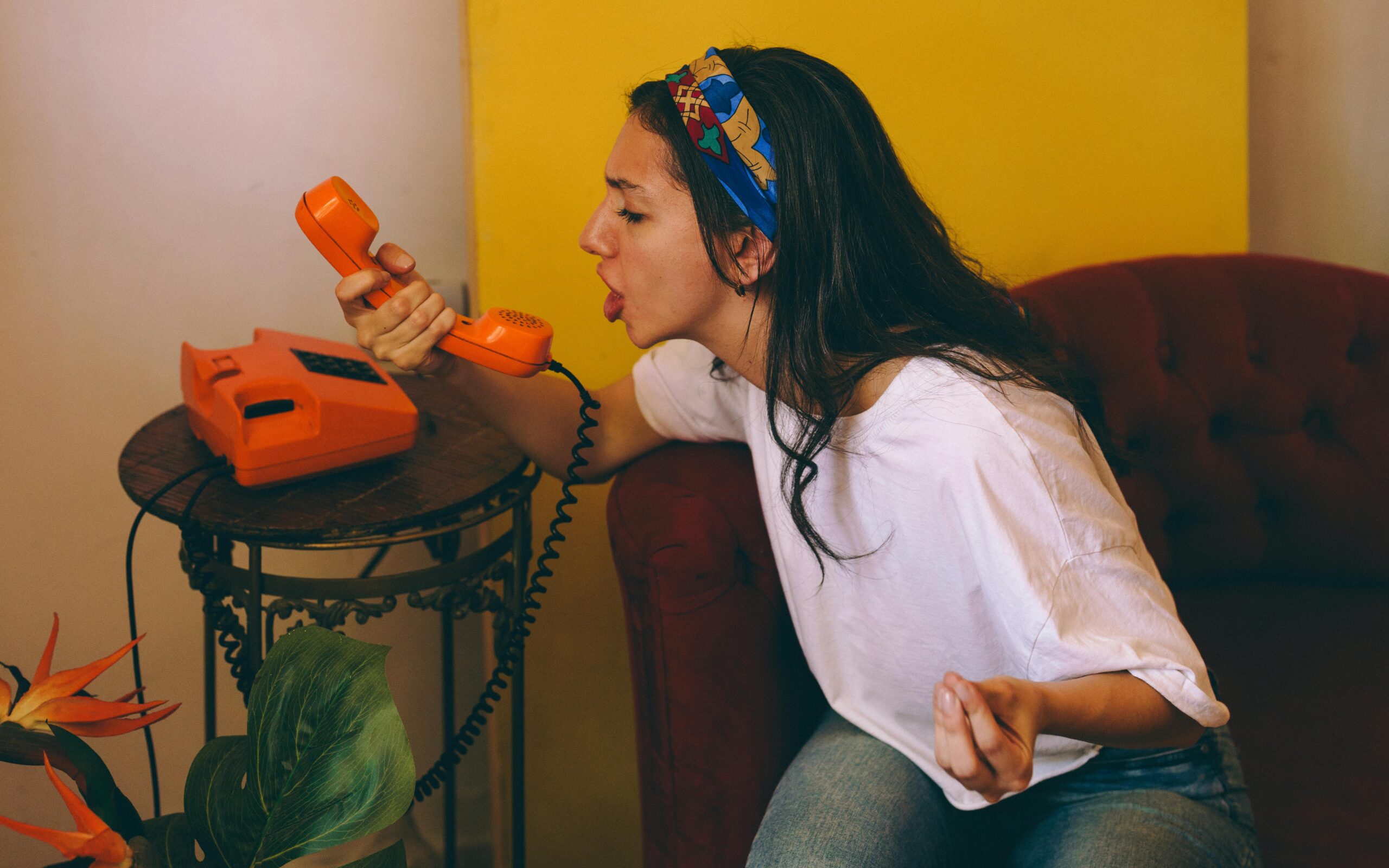 young-woman-yelling-into-retro-orange-phone