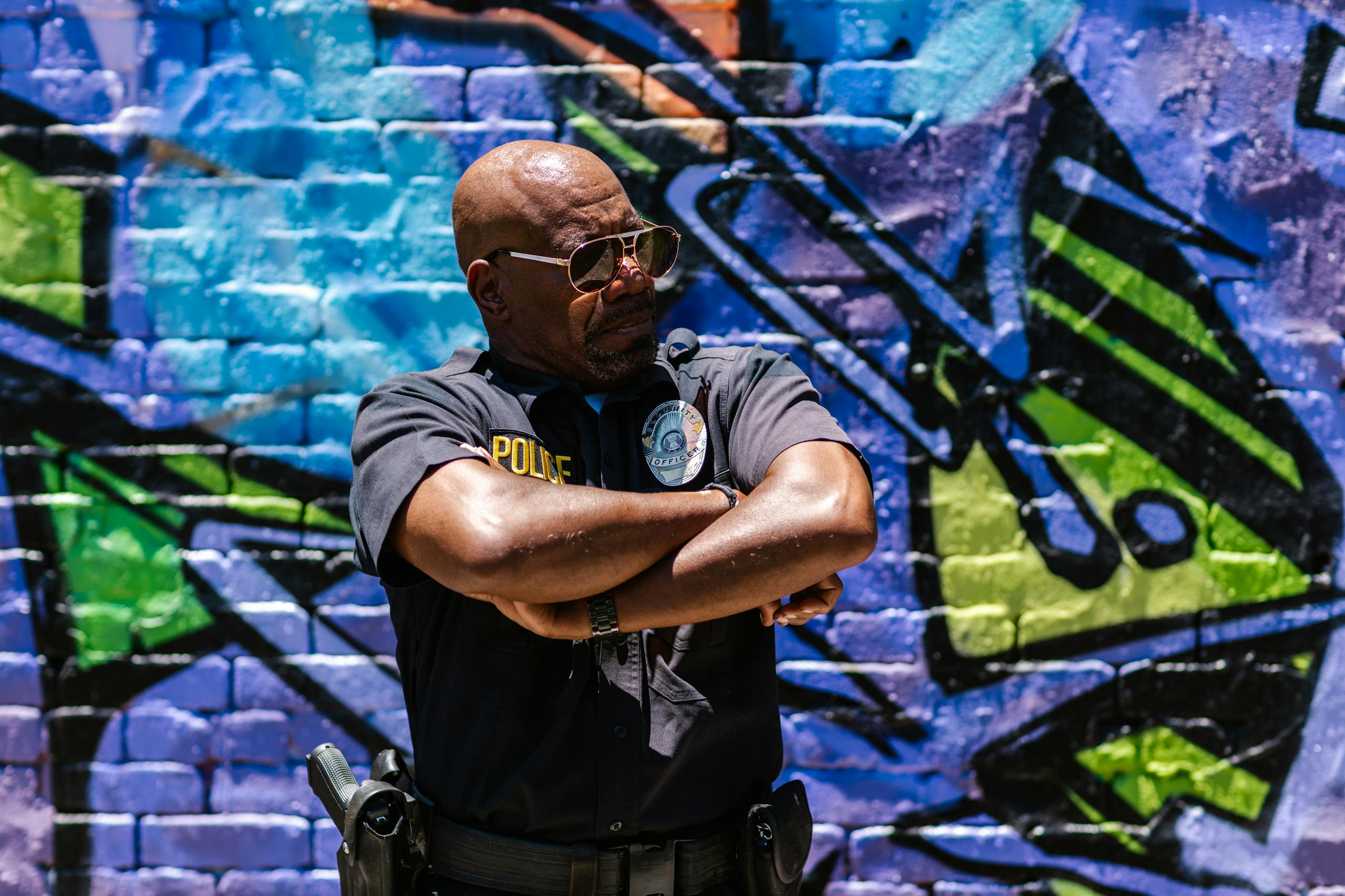 Police officer standing confidently against colorful urban graffiti wall.