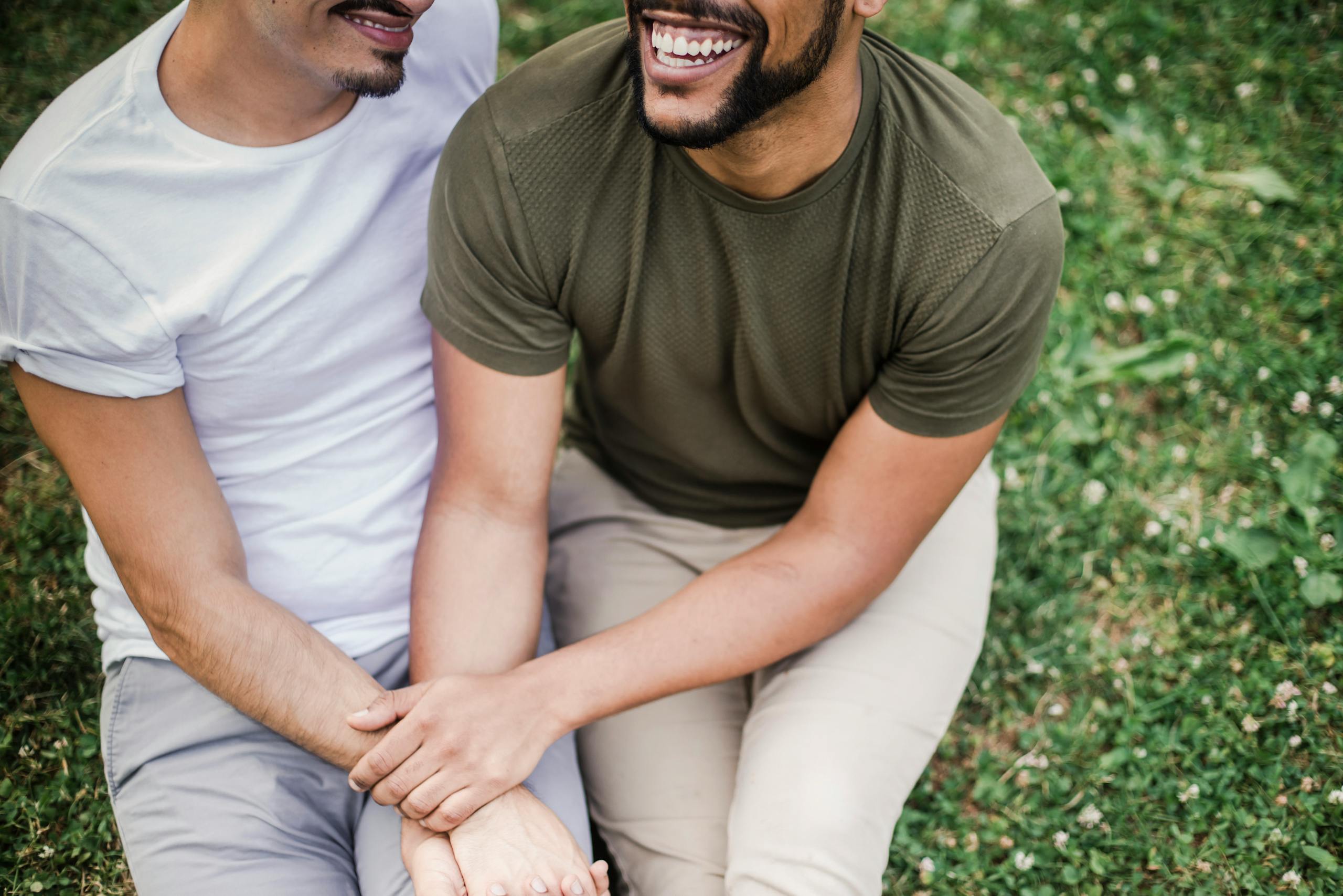 Smiling couple sitting outdoors, holding hands and enjoying quality time together in a park.