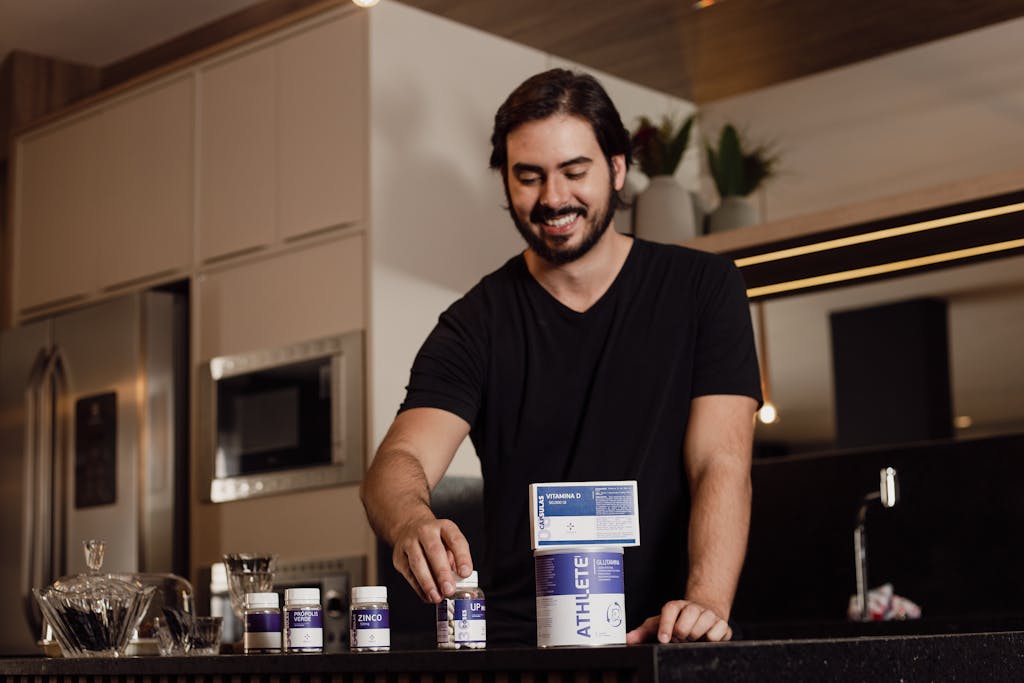 Smiling man arranging vitamin supplements on kitchen counter.