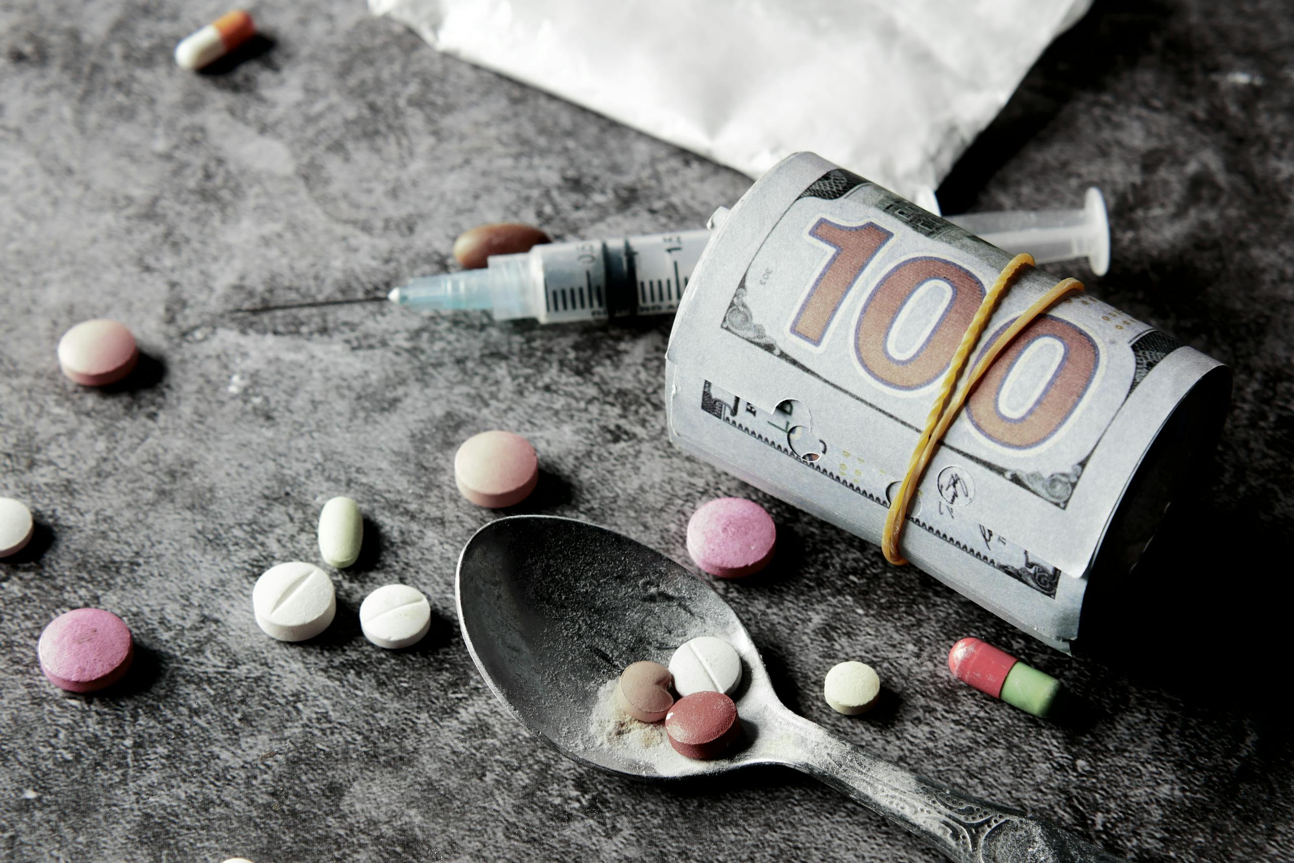 Symbolic representation of drug addiction and financial cost with pills and money.