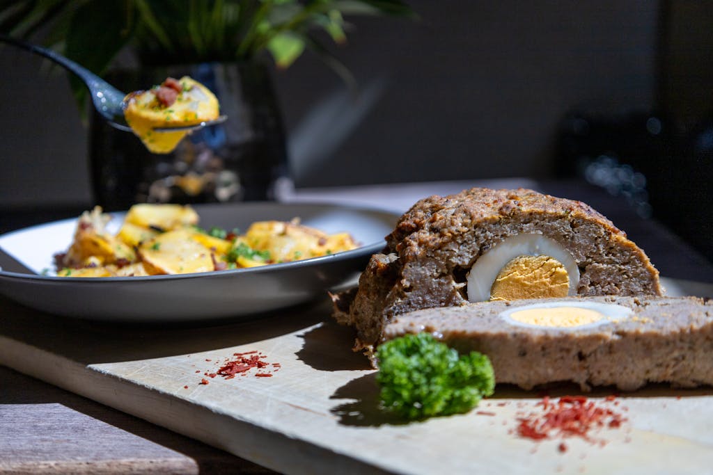 Tasty meatloaf with egg centerpiece served with potatoes. Perfect for a hearty meal.