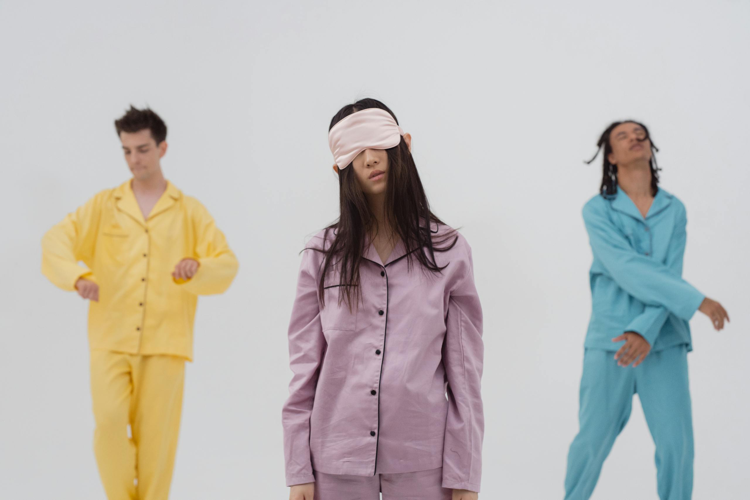 Three individuals in colorful pajamas and eye masks posed for a dreamy, surreal scene.