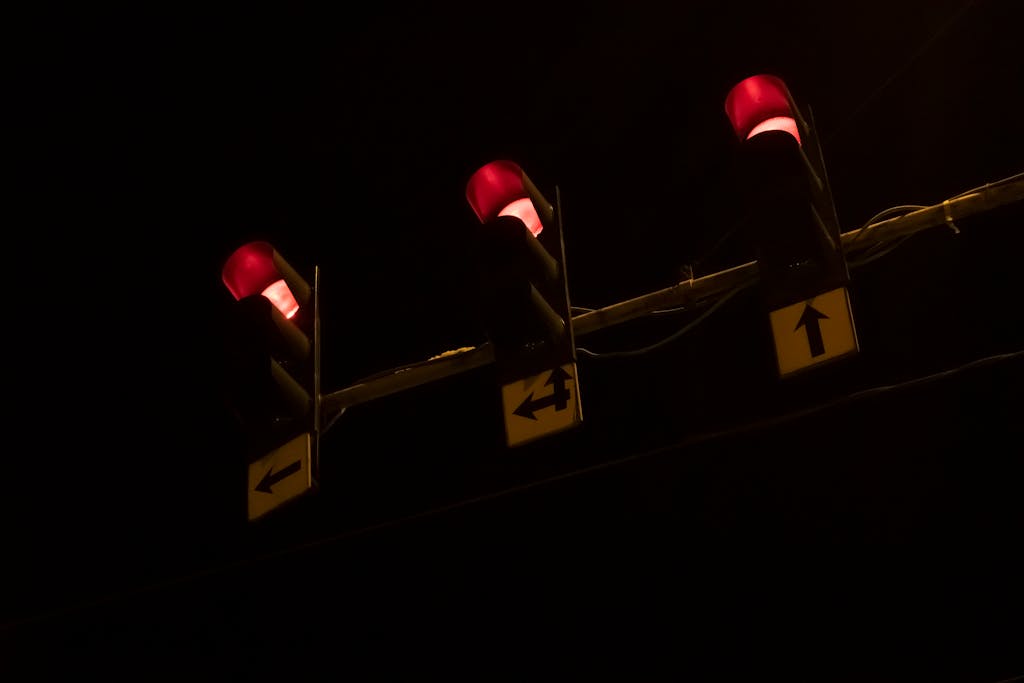 Three red traffic lights glowing brightly against a dark night sky, creating a vivid contrast.
