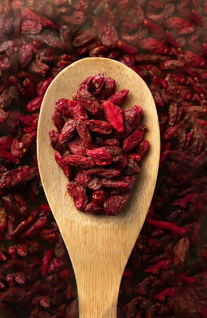 Top view of dried goji berries on a wooden spoon, emphasizing natural texture and rich color.