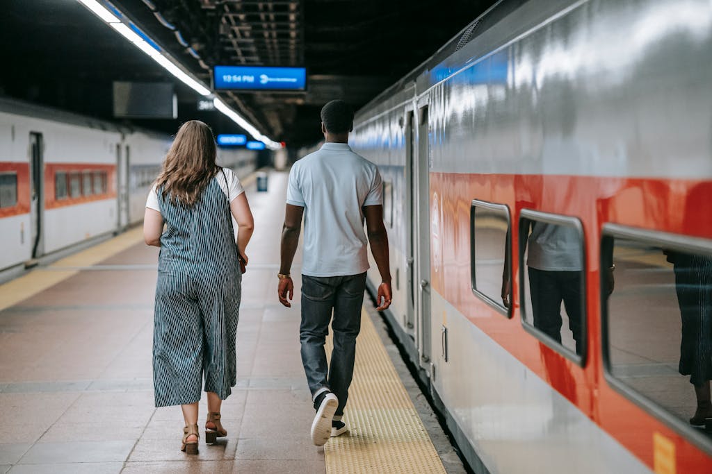 Two adults walking on train station platform, captured from behind.