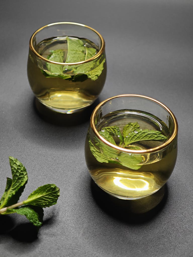 Two glass cups of mint tea with mint leaves on a dark background. Perfect for relaxation themes.