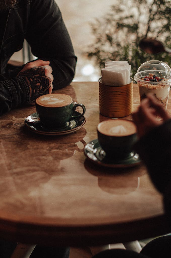 Two people enjoying cappuccinos at a cozy café, creating a warm and inviting atmosphere.