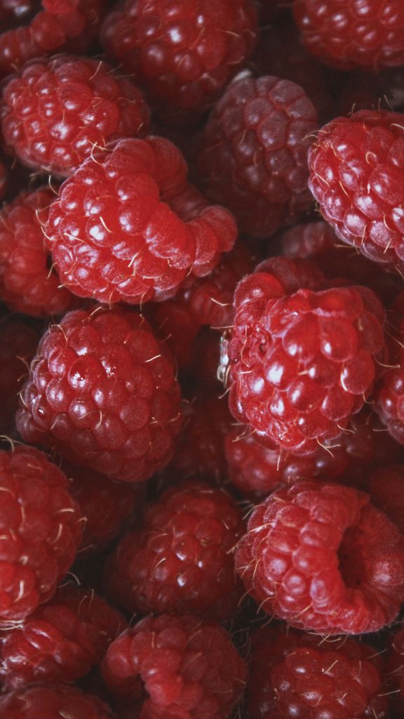 Vibrant close-up photo of ripe red raspberries with detailed texture.