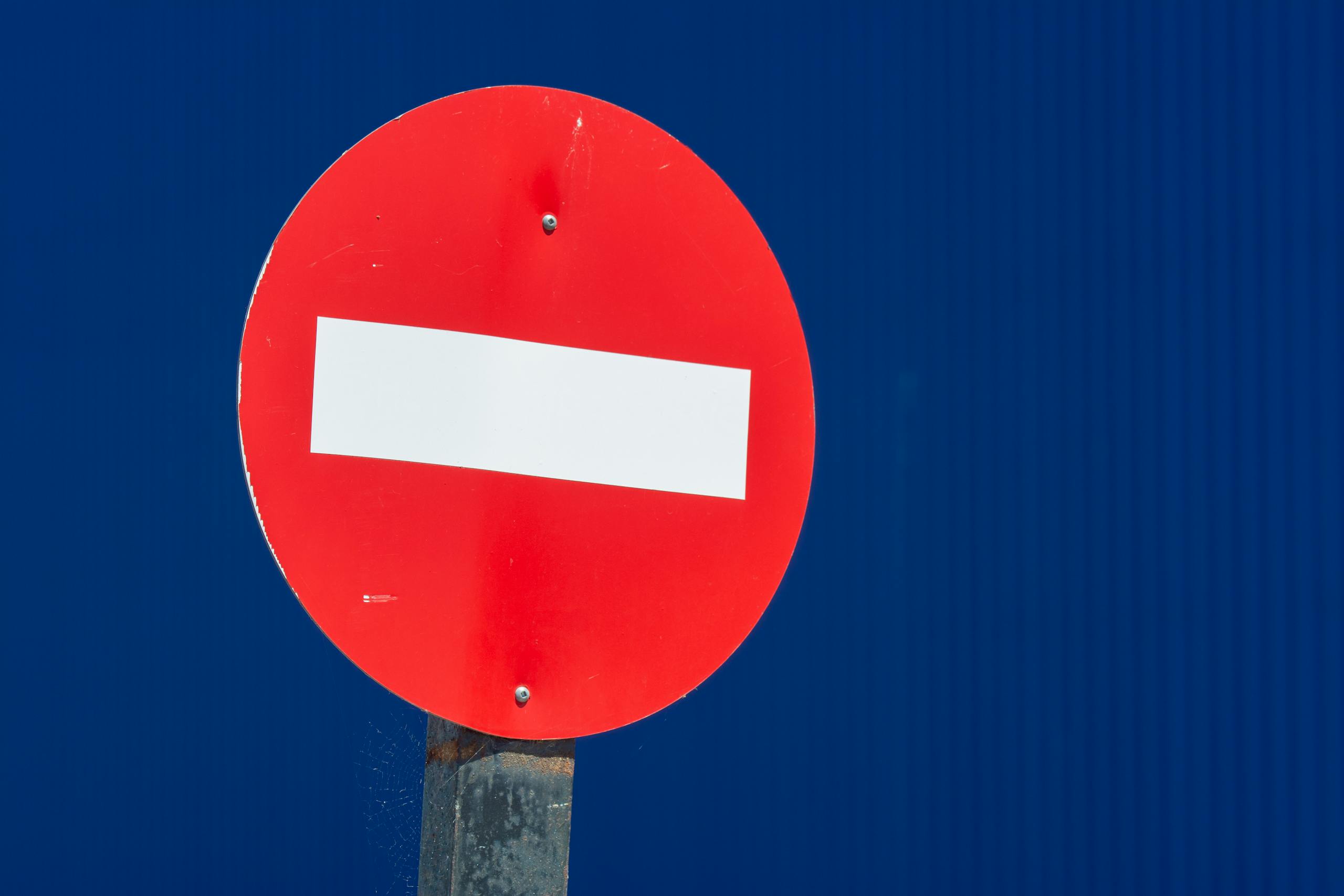 Vivid red do not enter sign with white bar on blue backdrop, ideal for travel warnings.