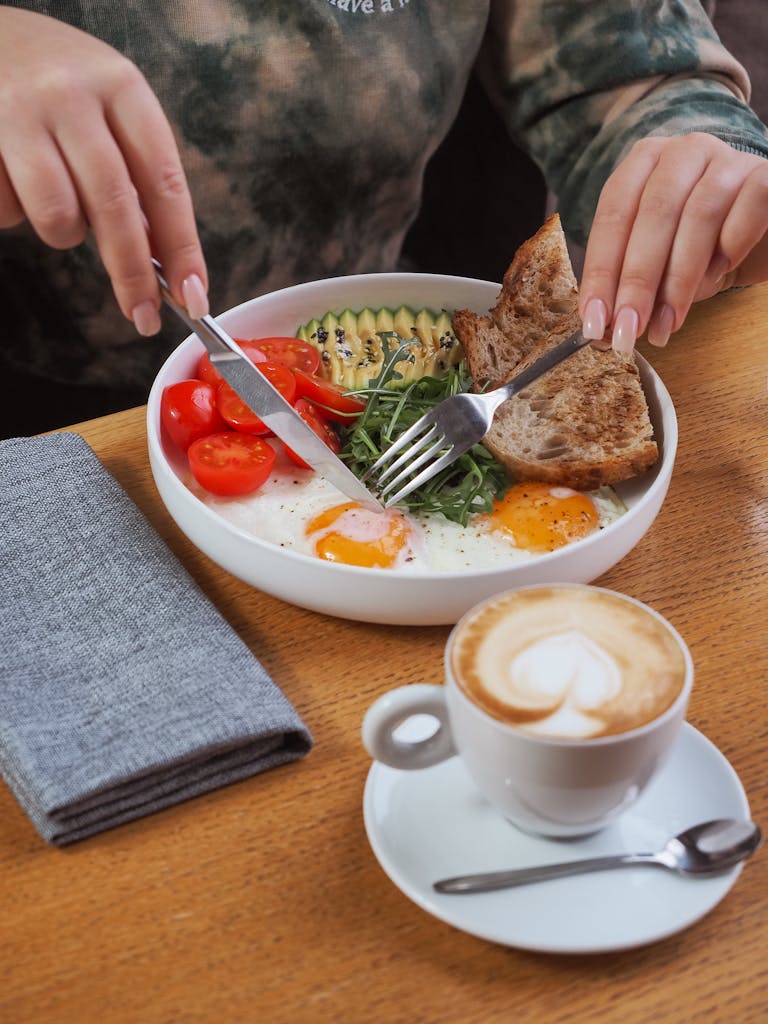 Woman enjoying a hearty breakfast with coffee, fried eggs, and avocado.