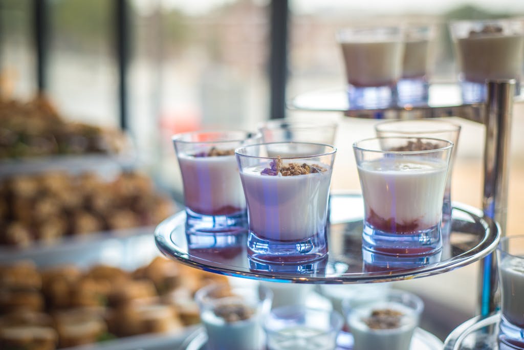 Yogurt parfaits elegantly displayed in glasses on a multi-tiered tray at a catering event.