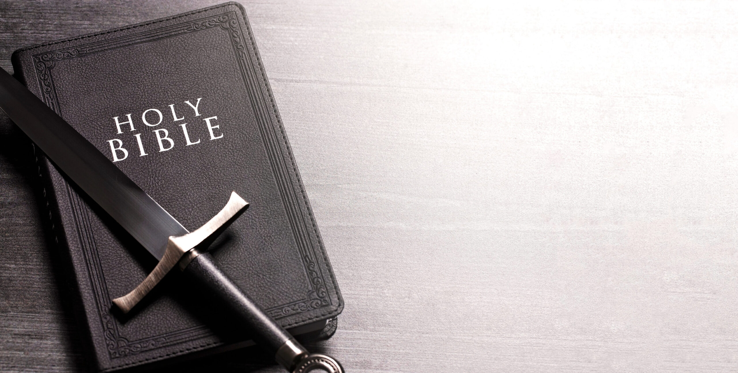 Bible and a Sword on a Dark Wooden Table