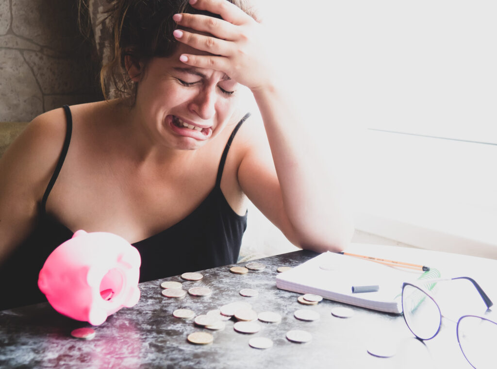 A girl with a piggy bank, she has no money, she looks at pennies and cries. Counts expenses and utilities, poverty