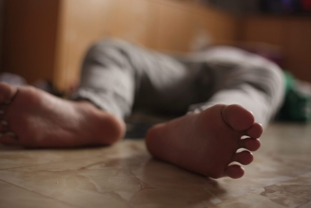 Barefoot man lying on floor, unconscious or dead, drugs overdose suicide, stroke heart attack health issue, or murder victim concept
