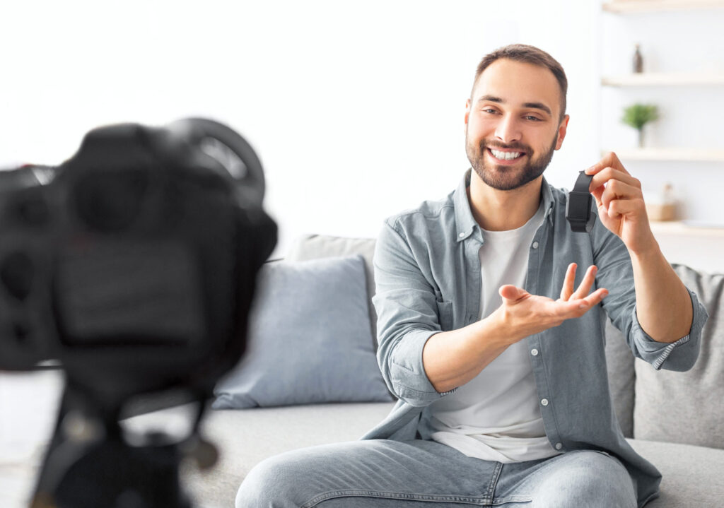 Young male influencer recording video content at home, making review on new smartwatch model