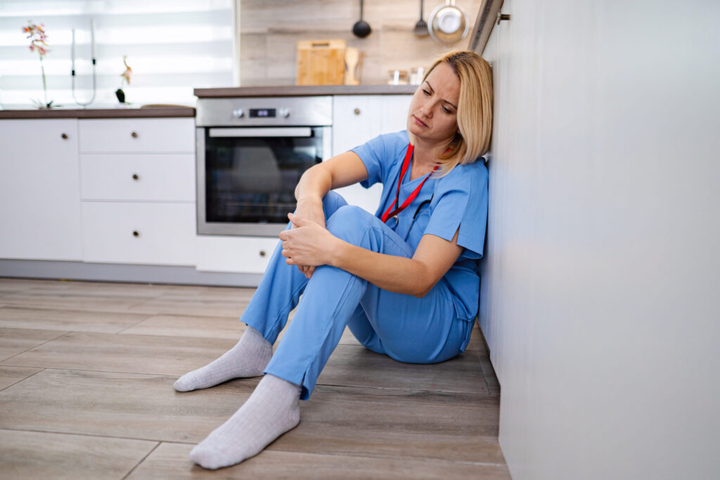 Exhausted doctor sitting on the floor in the kitchen