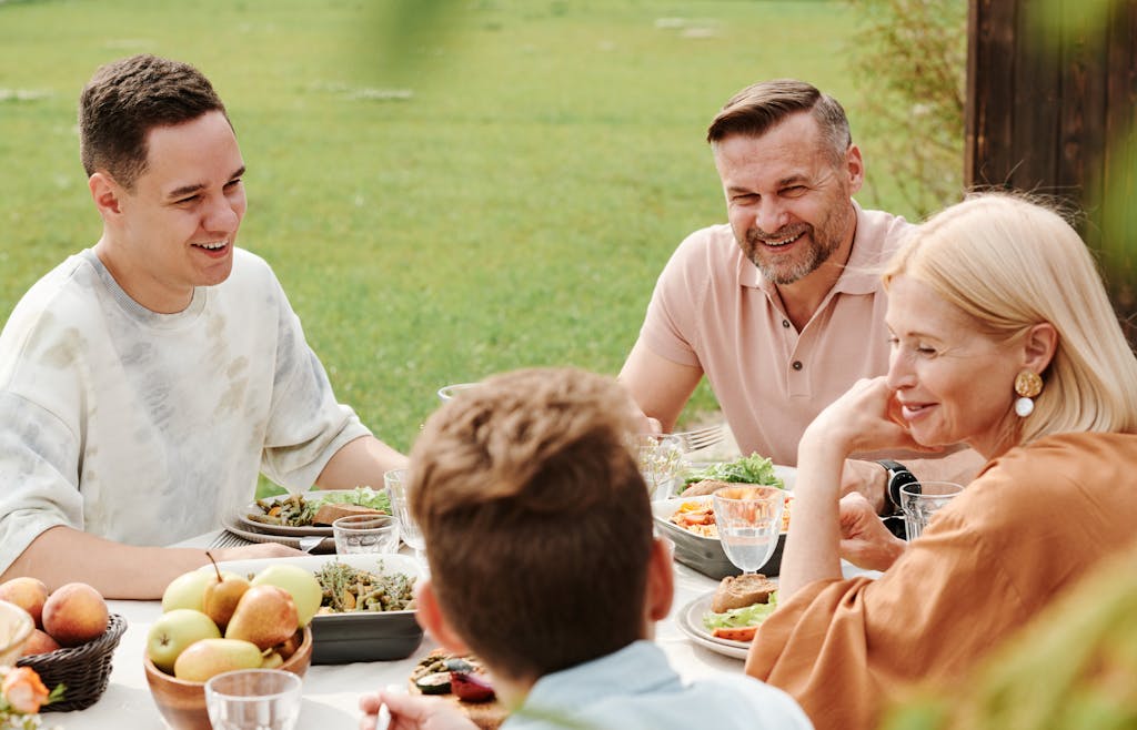 A cheerful family enjoying a meal together outdoors, sharing laughter and warmth.