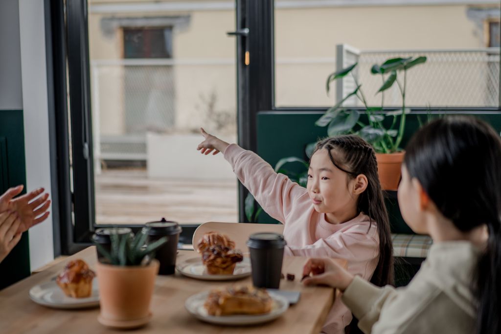 A family enjoys breakfast together indoors with coffee and pastries.