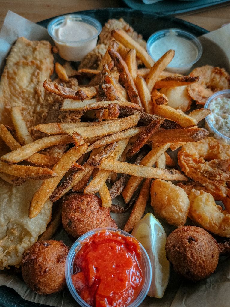 A mouth-watering platter of fried fish, shrimp, and fries with a variety of dipping sauces.
