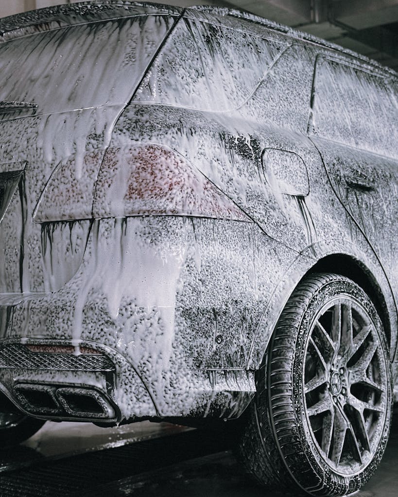 A premium SUV being cleaned with foamy soap in a detail car wash facility.