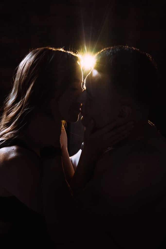 A romantic silhouette of a couple kissing, beautifully backlit, capturing intimacy and affection.