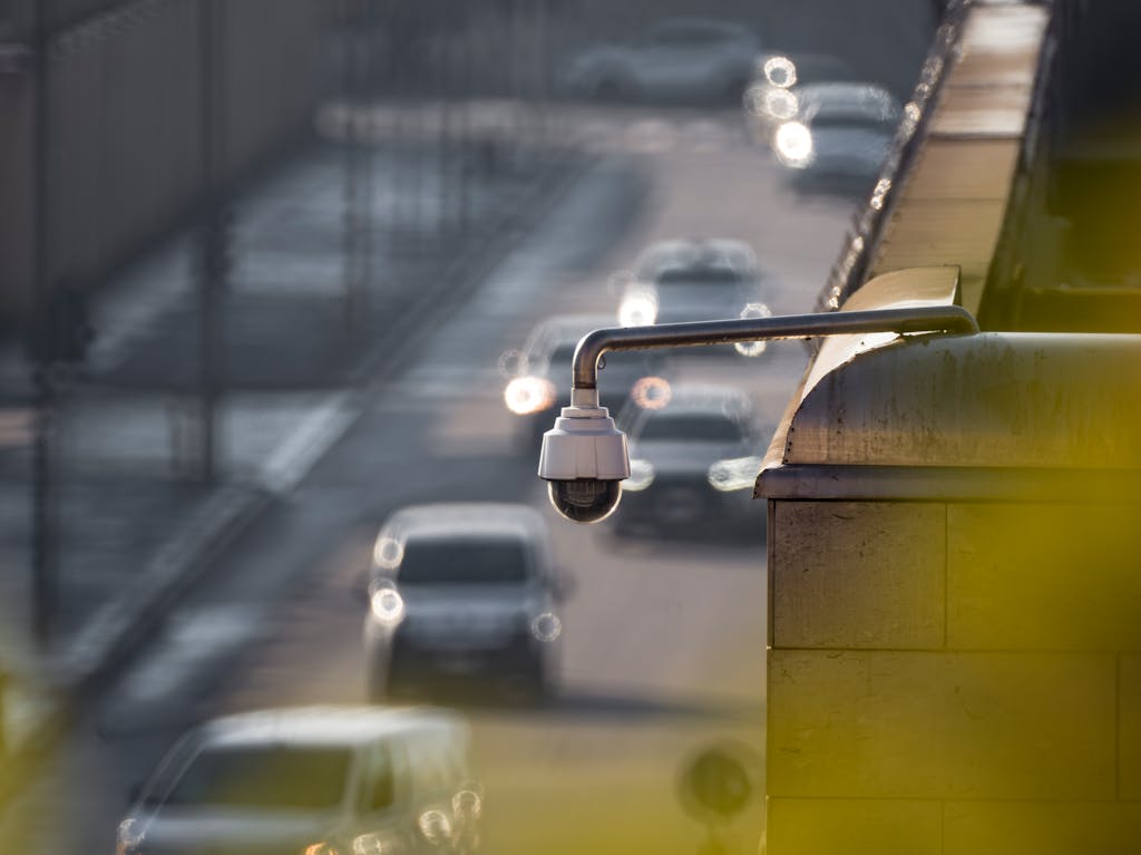 A security camera monitoring activity on a bustling city street with multiple cars in the background.