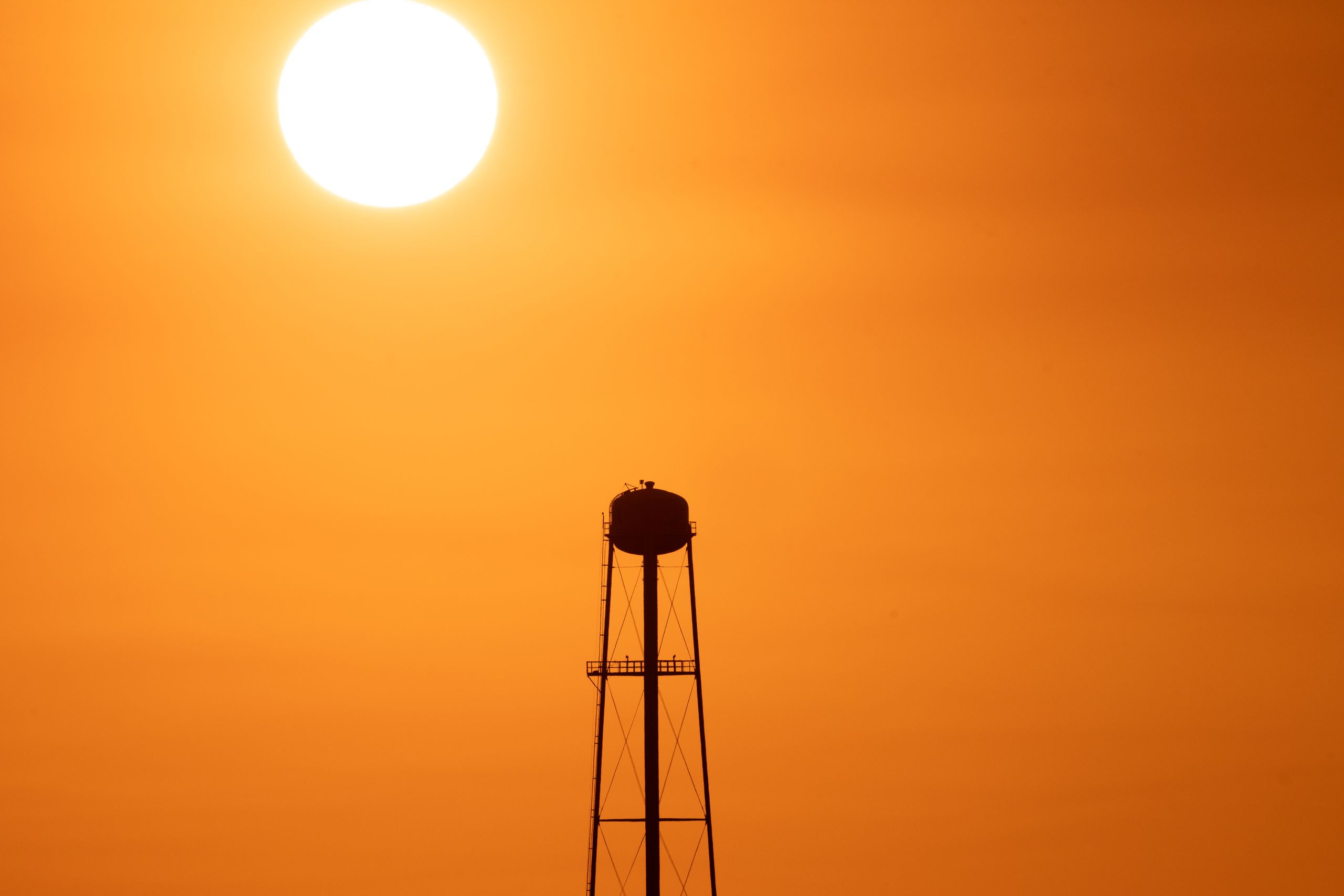 A striking sunset silhouette of a water tower against a vivid orange sky in Mather, CA.