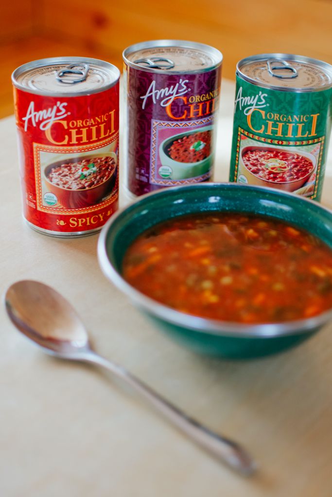 A vertical shot of organic chili served in a ceramic bowl, with canned chili options nearby.