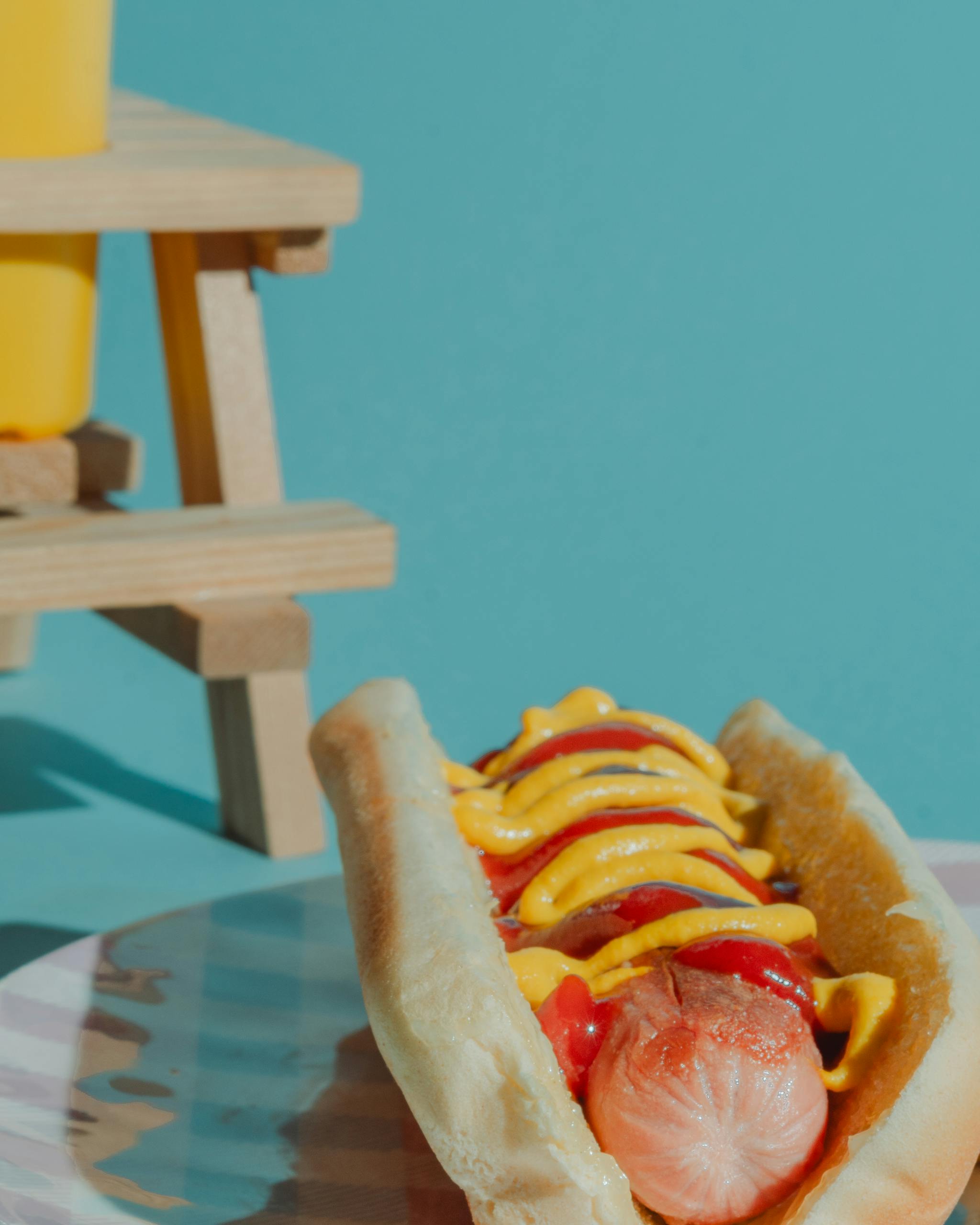 A vibrant image of a classic hotdog topped with mustard and ketchup on a sunny day.