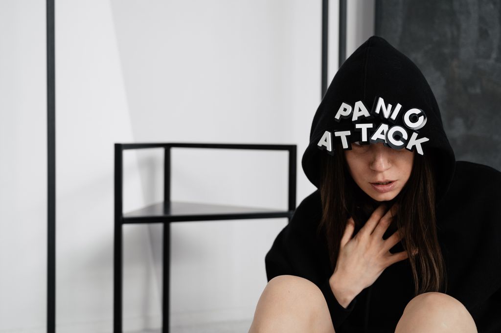 A woman in a hoodie with panic attack letters, representing mental health struggles.