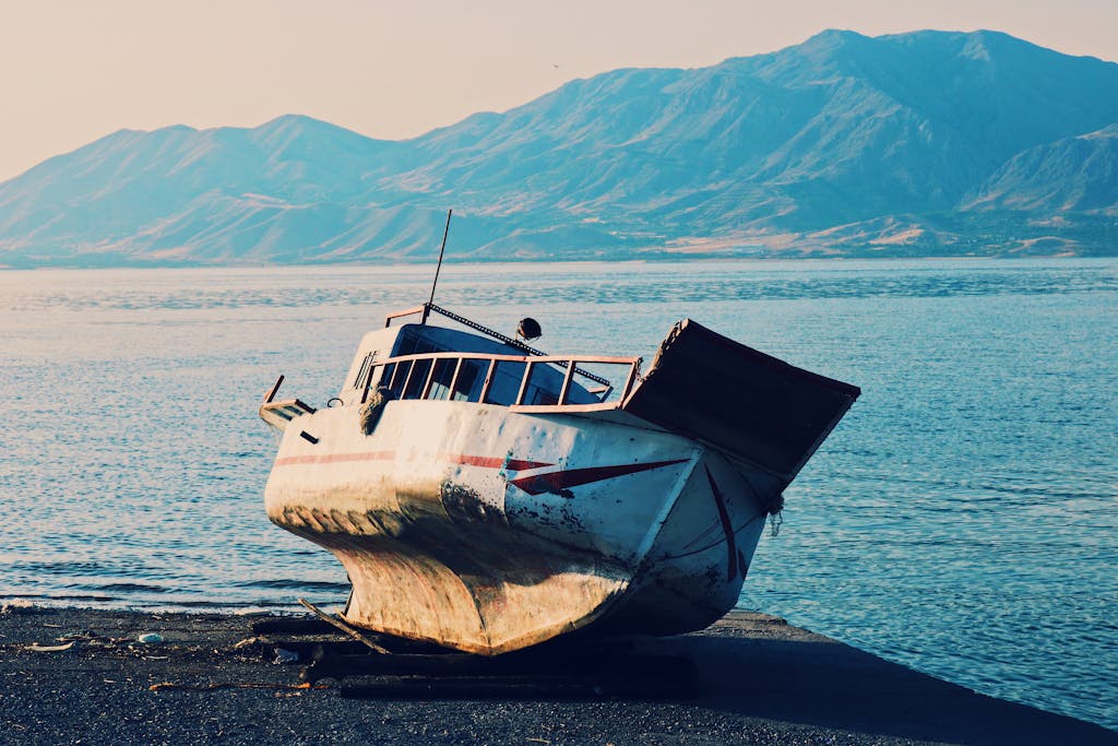 An abandoned boat on the shore with majestic mountains and a tranquil sea in Elazığ, Turkey.