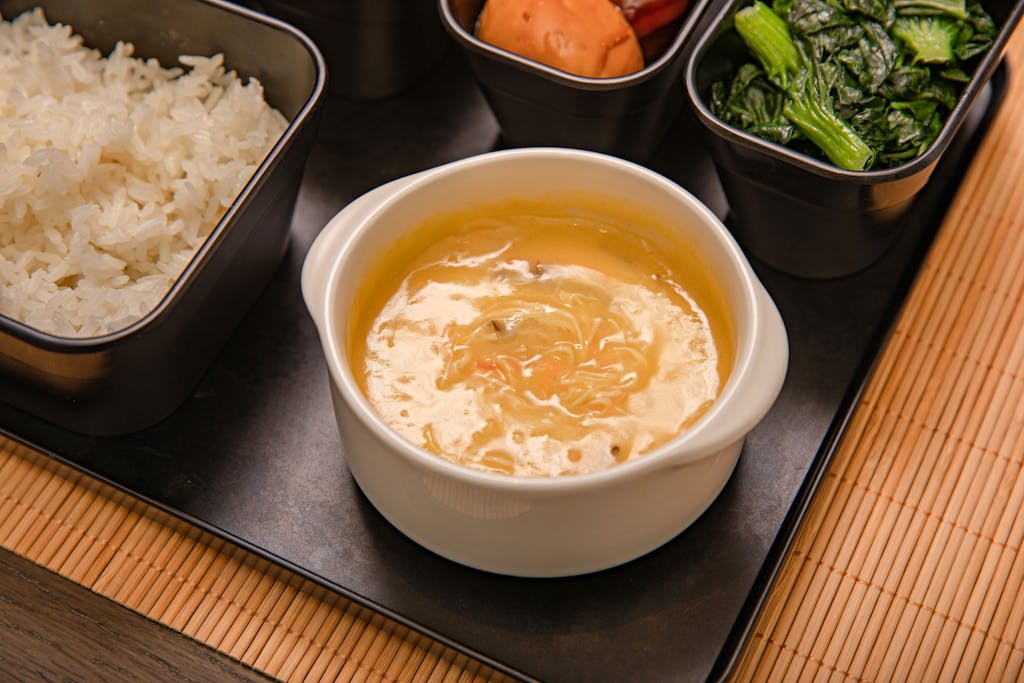 An appetizing Asian meal set with rice, soup, and vegetables, elegantly presented for a delightful dining experience.