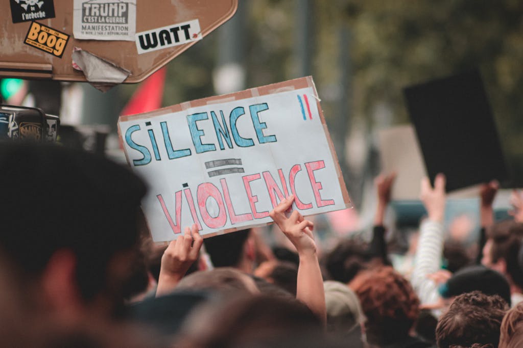 Anonymous person with poster Silence is Violence standing near board with stickers during peaceful Black Lives Matter protest