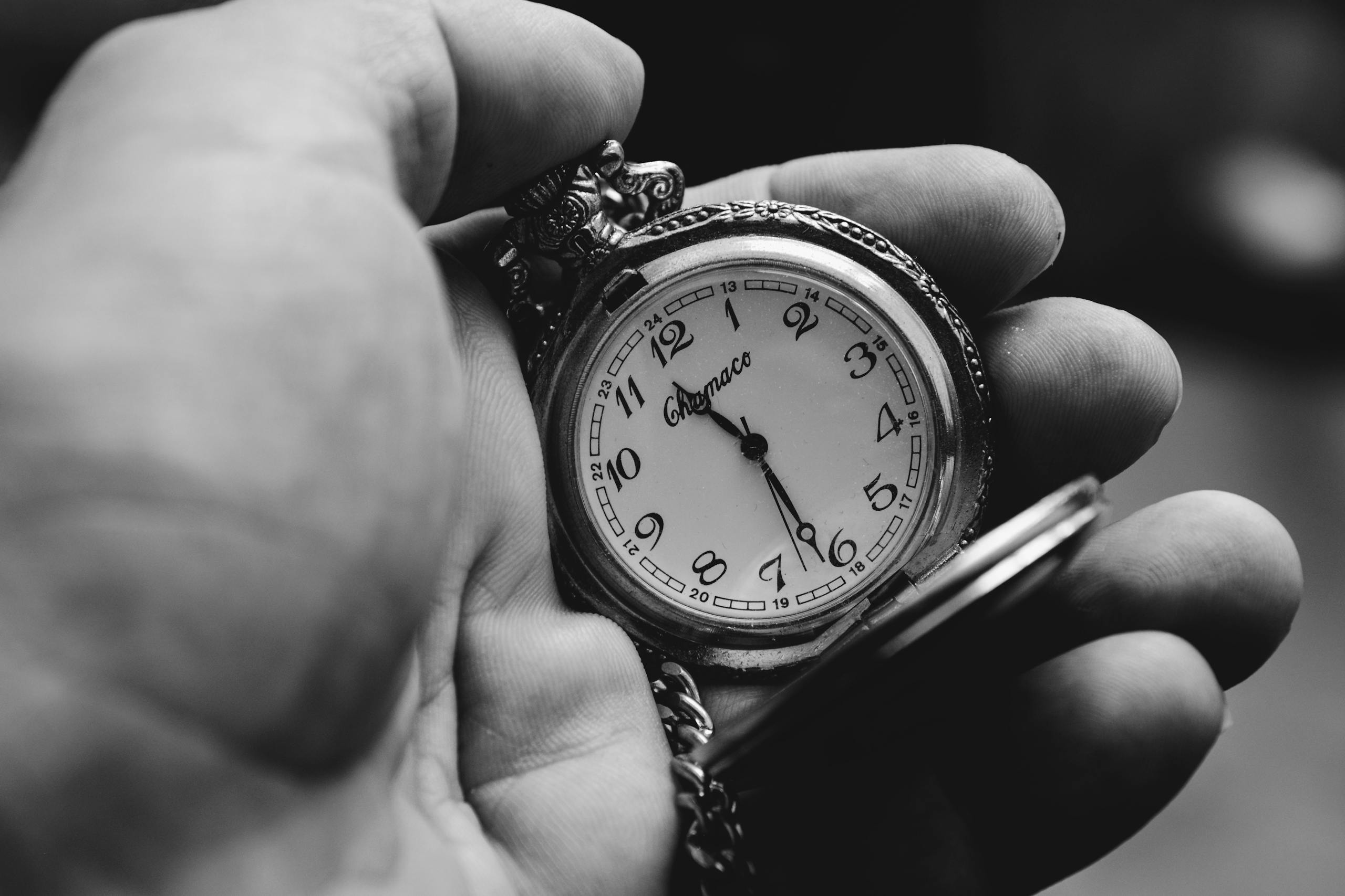 Black and white photo of a classic pocket watch in hand, showing time and elegance.