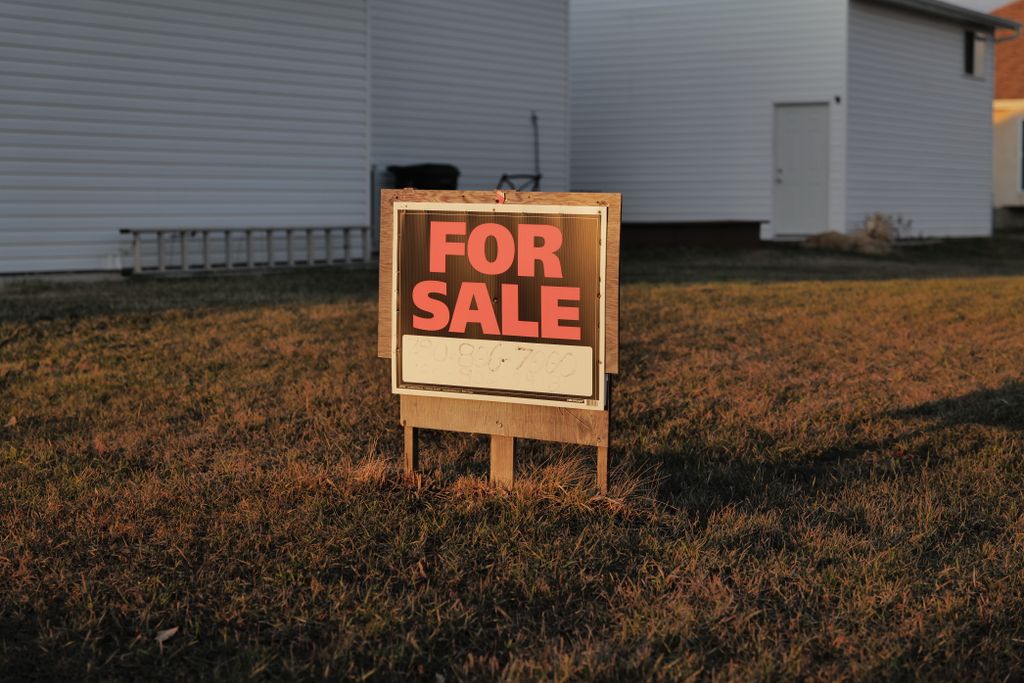 Close-up of a 'For Sale' sign in a suburban yard, indicating a property for sale.