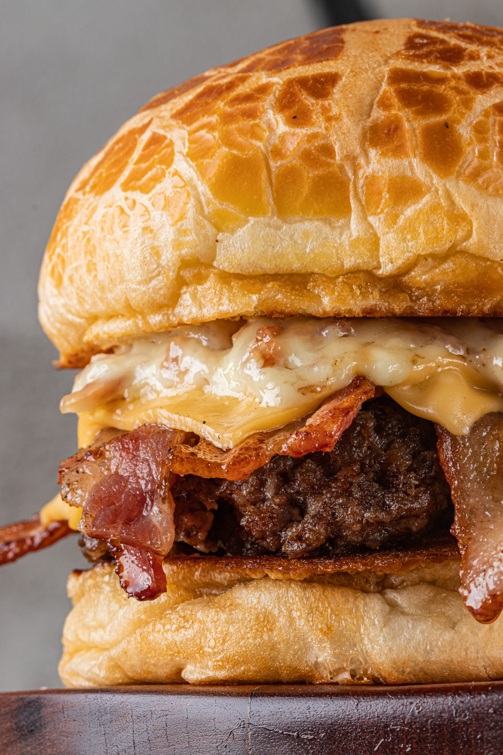 Close-up of a mouthwatering cheeseburger with crispy bacon and melted cheese, perfect for junk food lovers.