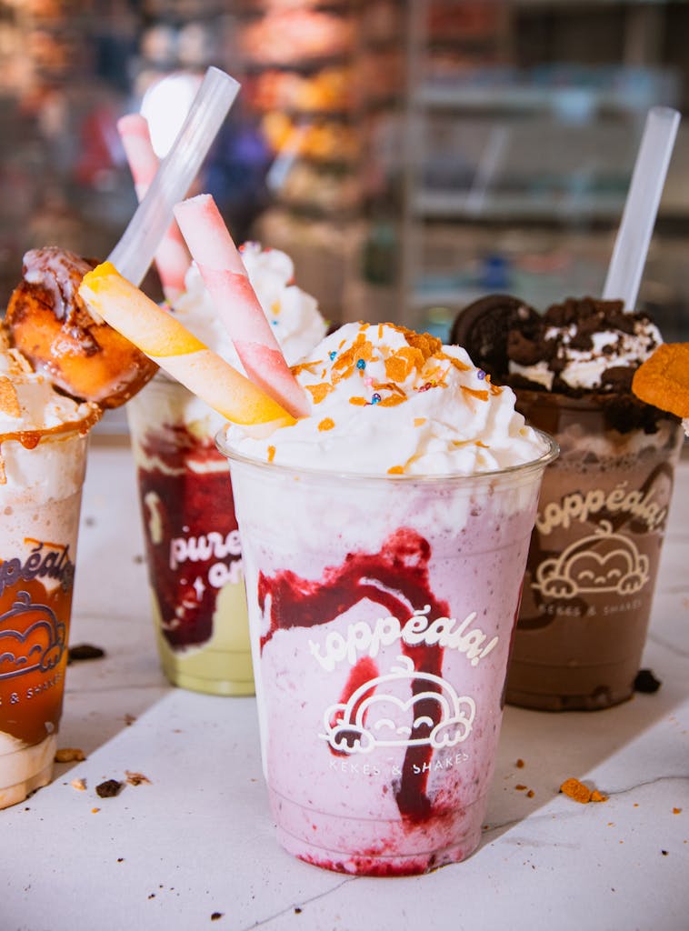 Colorful milkshakes topped with whipped cream and candy decorations in various flavors.