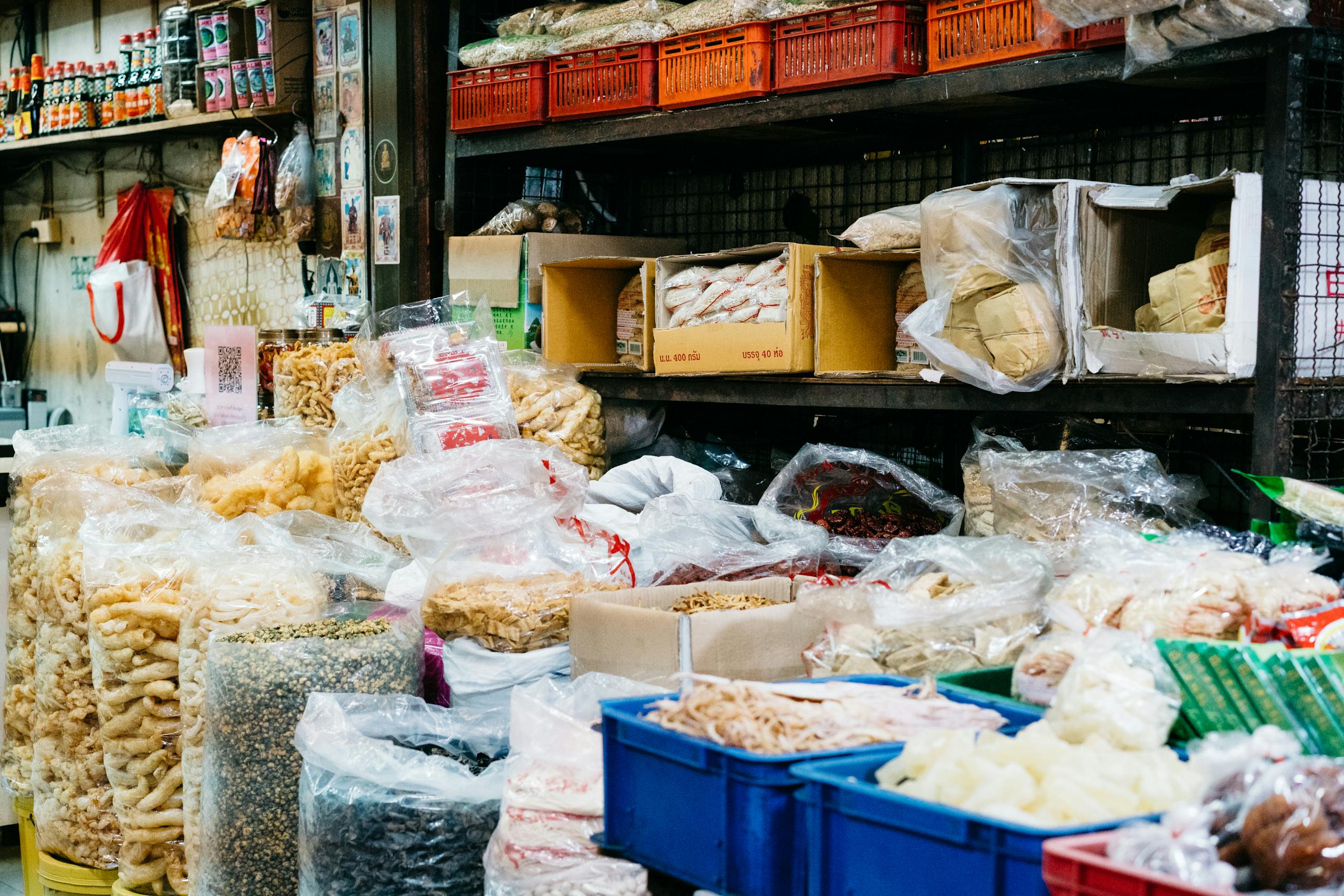 Colorful street market stall displaying a variety of dry foods in bags and boxes.